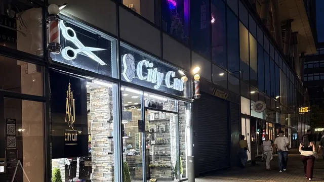 The AJ City Cut shopfront, lit up at night